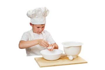 A child boy in white chef's clothes cooks food in a home kitchen, isolated on a white background