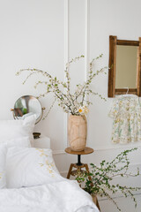 A vase with beautiful white flowering branches on the bedside table in the bedroom