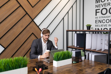 businessman in the office on a laptop in headphones watching a webinar