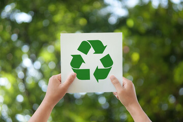 Hand holding recycle symbol on green bokeh background. Ecological and save the earth concept. An...