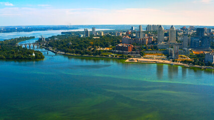 Fototapeta premium Beautiful urban environment on a summer day. Aerial view of the summer landscape with a view of the river and the city on the shore.