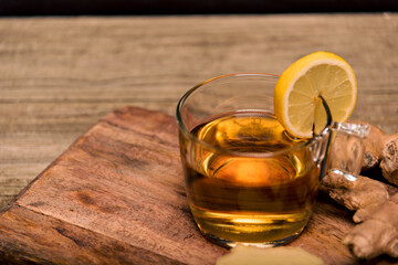 Cup of hot tea with ginger root, lemon and curcuma. Adding natural raw honey to cup of hot tea. Vitamin C drink, immune system boost.