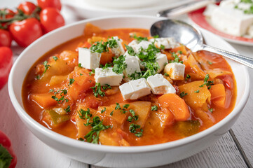 Vegetable soup with cabbage and feta cheese topping on a plate. 