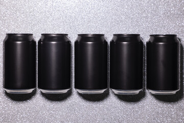 Photo of five black blank aluminum cans in a row with hard lighting on a silver background with...