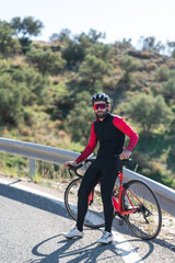 Cyclist sitting down on his bike at the road near to the mountain. Looking the camera