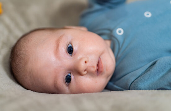 Portrait of adorable baby boy lying on the bed on his side. First photo shoot. Newborn baby.