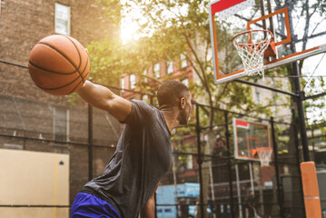Basketball player training outdoors - Athlete playing basketball in a playground court outdoors