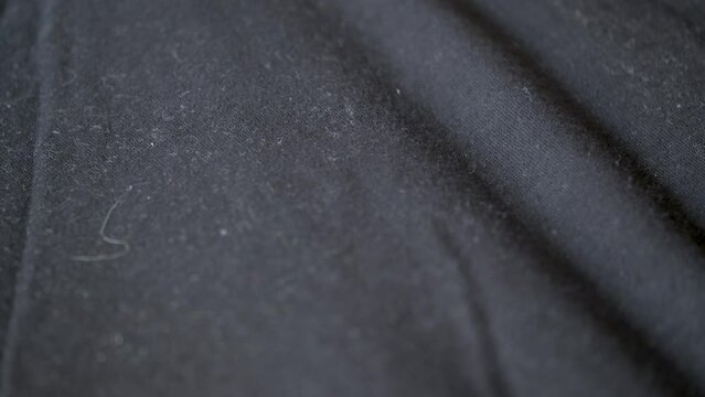 Close up of someone using a sticky lint remover roller for clothes over black t-shirt.