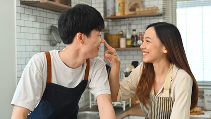 Happy young couple having fun cooking together in kitchen, spending leisure weekend at home together. Romantic moment