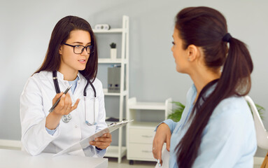 Doctor explains to female patient her diagnosis and treatment methods after medical examination....