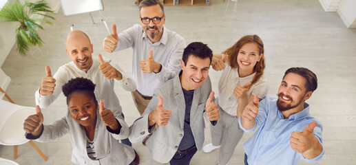 Team of happy smiling business people giving thumbs up together. Joyful diverse male and female...