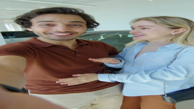 Vertical shot of cheerful young married couple bragging about buying new car on video call