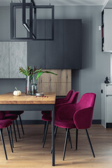 Stylish composition of elegant dining room interior design with velvet chairs, design wooden table, lamps, chimney and beautiful personal accessories. Modern home decor. Template.