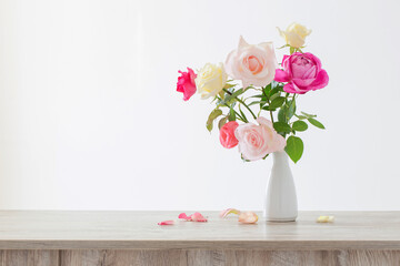 pink and white roses in white ceramic vase on white background