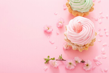 Fototapeta na wymiar pink and green cupcakes with spring flowers on pink background