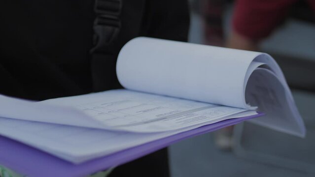 Filming staff checks script on paper for scene for upcoming movie. Crew prepares location and decorations for filming scene