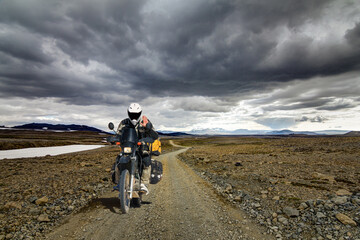 One Motorbiker Man driving on a gravel road in Kaldidalur desert. Motorcycle Adventure in Iceland. - 566963659