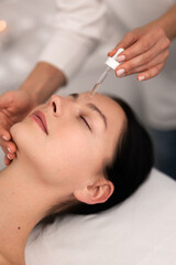 Obraz na płótnie Canvas Crop beautician applying serum on face of female client