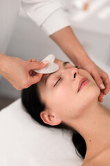 Crop beautician massaging forehead of client with gua sha