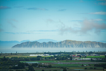 Mountain range rising up over the sea not far from green mainland. Gisborne, North Island, New Zealand