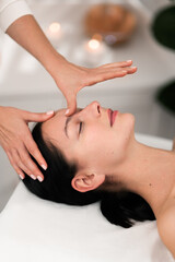 Crop masseuse doing acupressure facial massage to female client