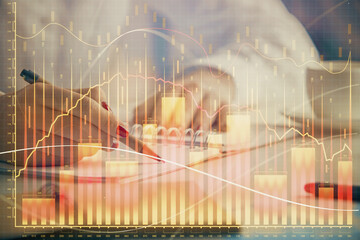 Double exposure of woman's hands making notes with forex graph hologram. Concept technical analysis.