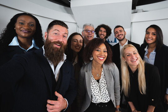 Selfie portrait with large mixed group of elegant colleagues smiling and looking at camera.