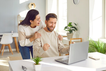 Family couple happy about a good job offer. Young man and woman looking at their laptop computer...