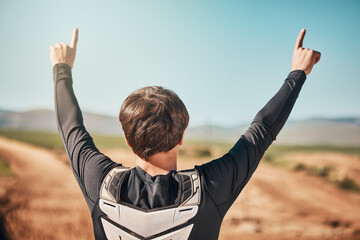 Fototapeta na wymiar Winner, hands and back of a sports man outdoor on a dirt track for racing, competition or adrenaline. Success, celebration and winning with a male athlete or biker standing hands raised outside