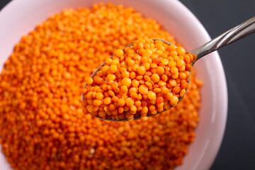 Red lentils in metal spoon. Top view, closeup.