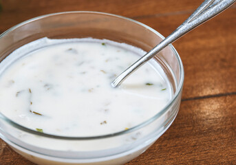 yogurt soup with herbs in a plate on a wooden table.spas