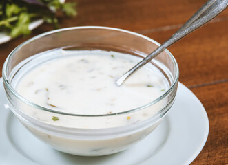 yogurt soup with herbs in a plate on a wooden table.spas