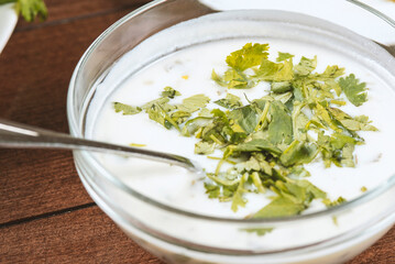 yogurt soup with herbs in a plate on a wooden table.spas
