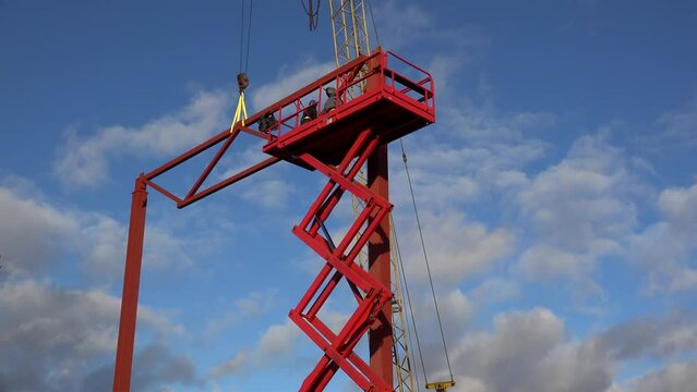 Workers are lifting on the Aerial Work Platform (Scissor lift) to secure the beam frame