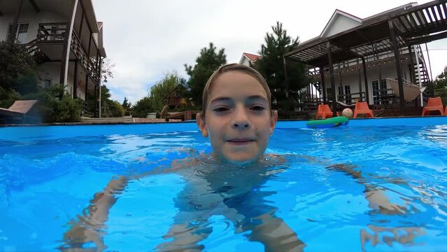 Child is diving into a blue water at summer day. Portrait of smiling young boy having fun in the swimming pool. Enjoying time on vacation