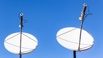 Satellite Dishes Digital Global Communications Two White Units Against Blue Sky Close Up Photograph.