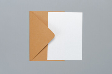 Above view studio shot of an envelope made of craft paper and blank white postcard isolated on grey background