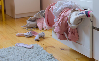 A pile of clothes in an open chest of drawers. A mess in the room of a child, girl, teenager. Copy...