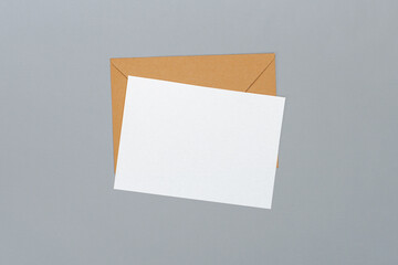 Above view studio shot of an envelope made of craft paper and blank white postcard isolated on grey background