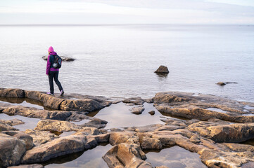 Woman walking on a rocky beach. Fäboda, Jakobstad/Pietarsaari, Finland.