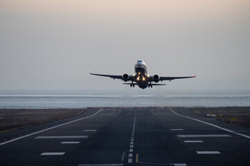 A frontal shot - an airplane takes off from an airport near the ocean shore in the evening