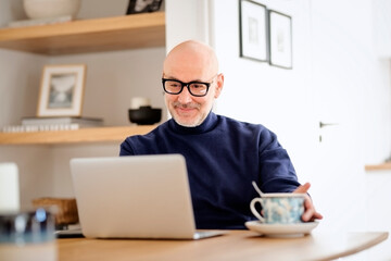 Middle aged businessman wearing casual clothes and using laptop while working from home