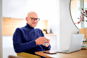 Middle aged businessman wearing casual clothes and using laptop while working from home