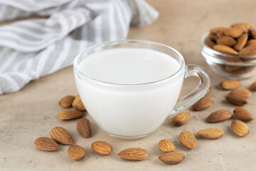 Almond milk in a glass cup and almond kernels on a light background. Copy Space. Selective focus.