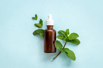 Green mint leaves with bottle of essential peppermint oil