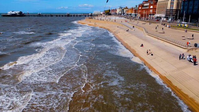 pier overhead view. Birds flying on the Ferris wheel and the pier. Waves crashing on the shore in the blue sea
