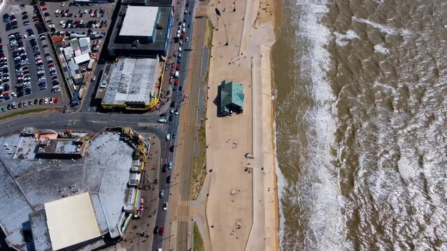 pier overhead view. Birds flying on the Ferris wheel and the pier. Waves crashing on the shore in the blue sea