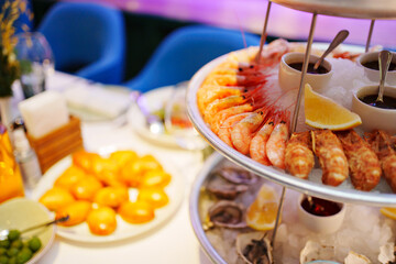 shrimp and shells with oysters on a platter with ice, lemons and sauce. 