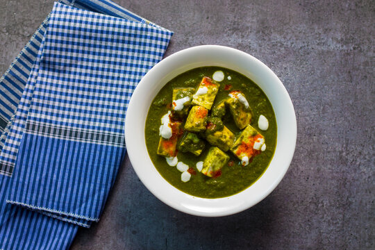 "Palak Paneer" Indian food made of spinach and cottage cheese with a white ceramic plate. 