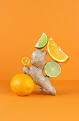 Balancing citrus fruits on the table. Citrus pyramid: lime, orange, ginger and lemon on an orange background. Ingredients for preparing a drink for colds and flu. Copy Space.